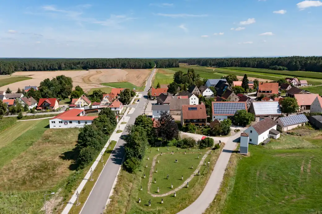 Luftaufnahme: ländliches Dorf, Häusergruppe, Felder, Solardächer, Landstraße.