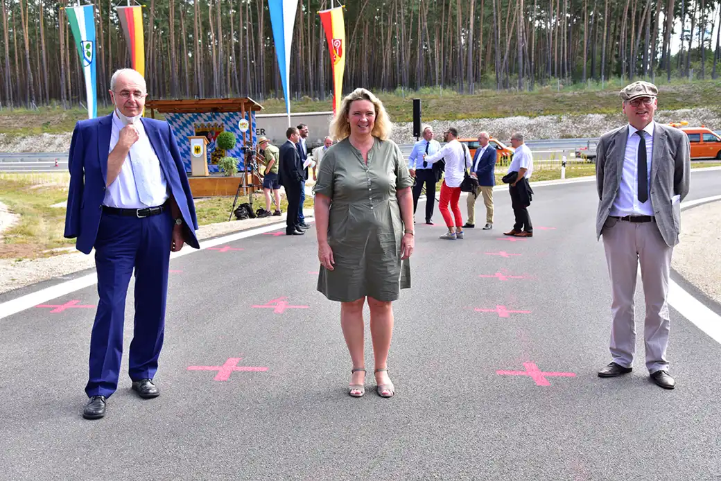 Drei stehen auf roten X; andere und Fahnen im Hintergrund in der Nähe des Waldes.