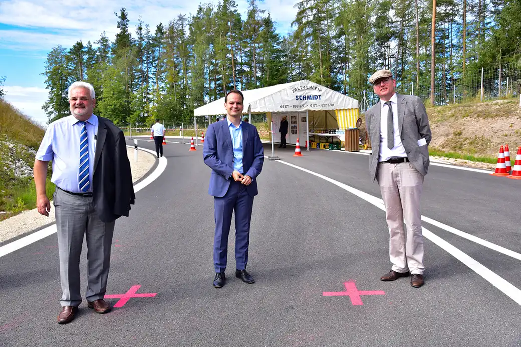 Drei Geschäftsleute stehen auf einer markierten Straße in der Nähe eines Zeltes und von Kegeln.